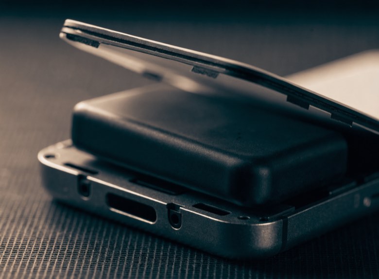 A swollen phone battery bulging inside an opened chassis, pushing the back panel away.